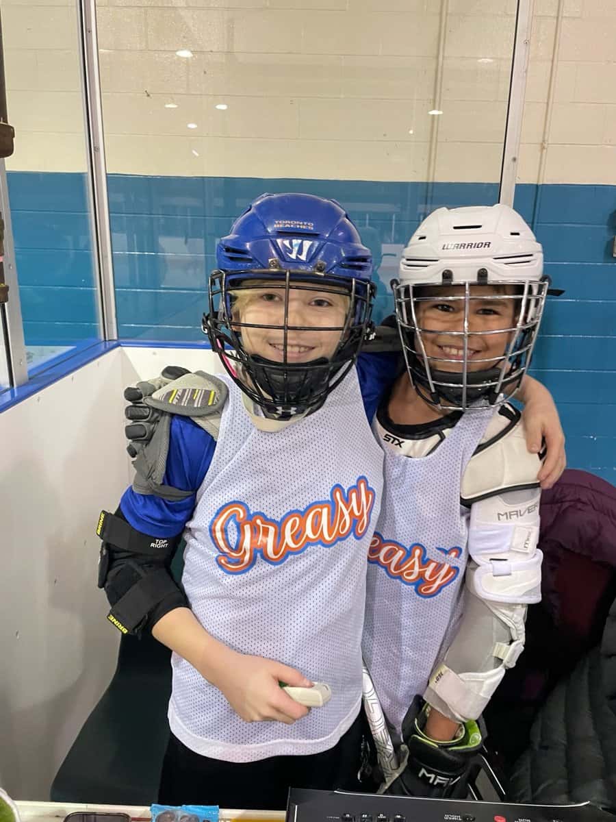 Two Greasy Ballers teammates arm in arm at the rink