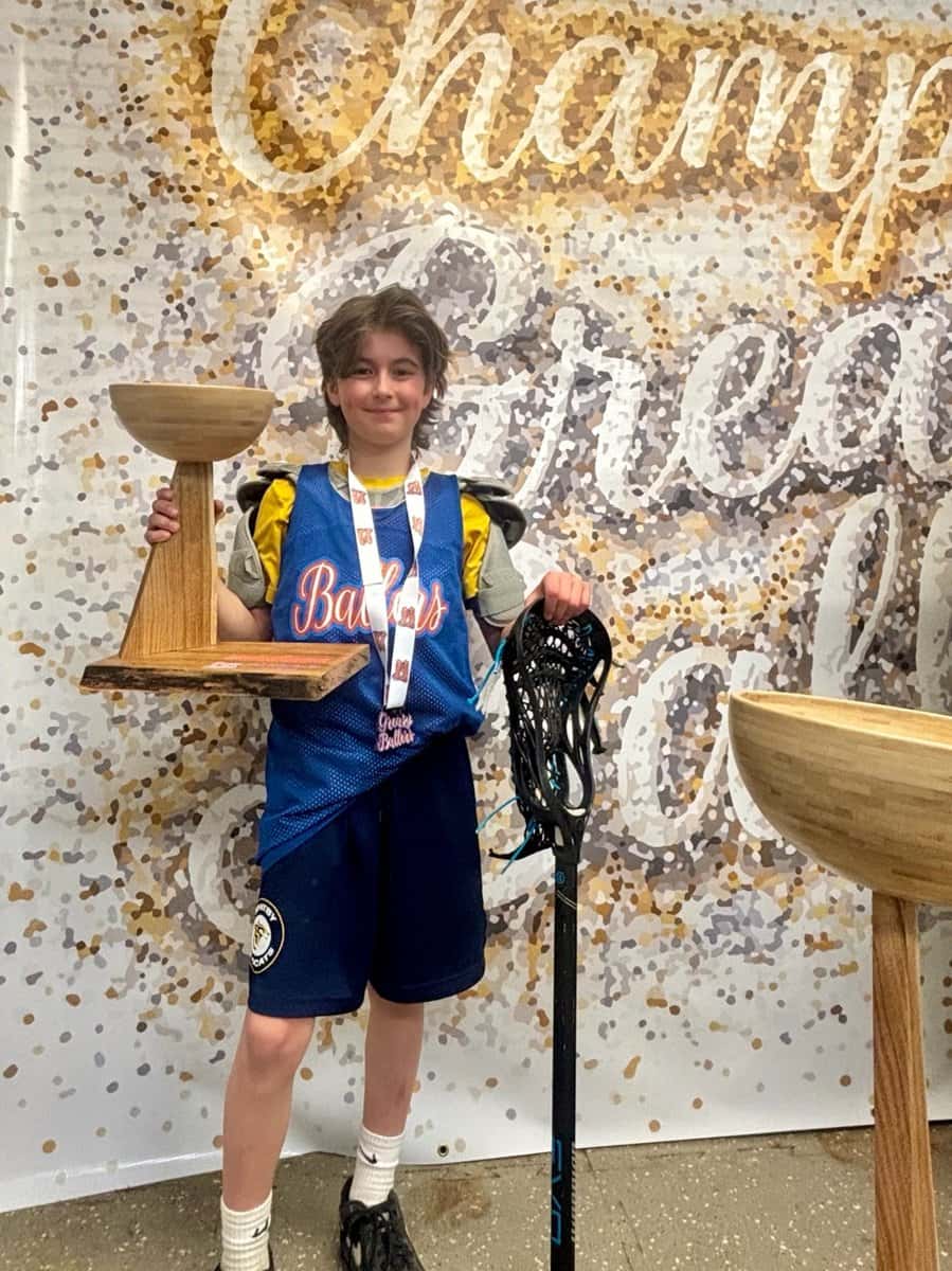 Greasy Ballers champion holding the wooden trophy