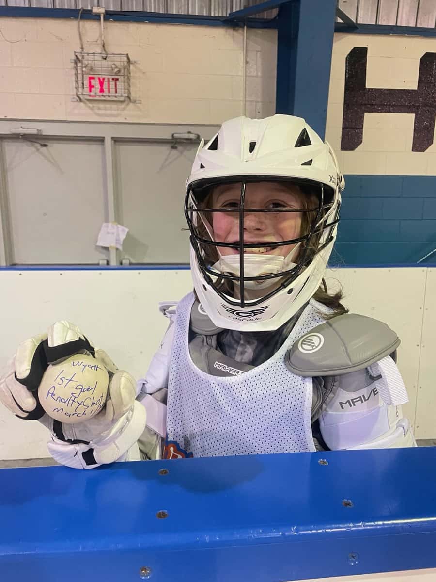 Greasy Ballers goalie holding her signed first-goal ball